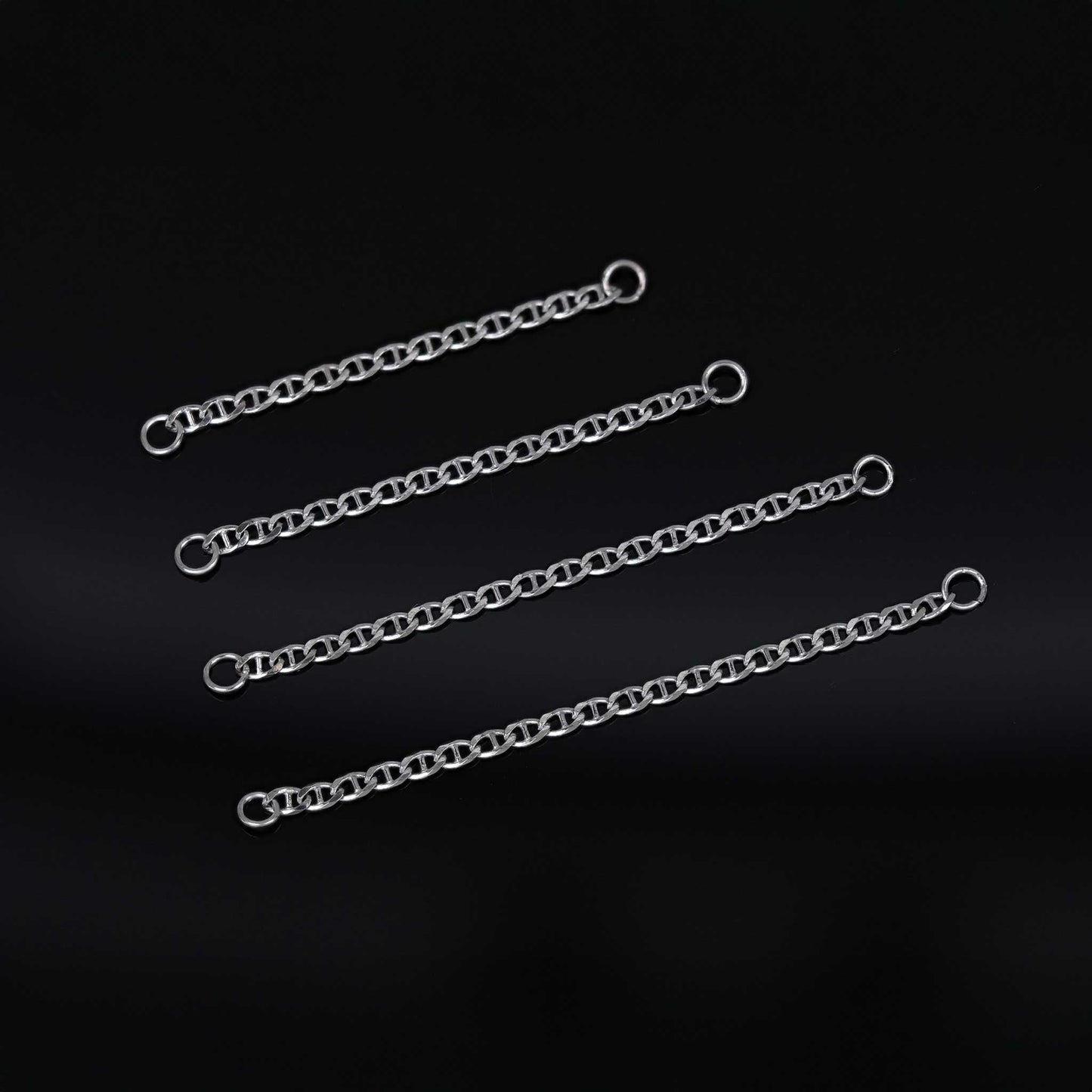 Four white gold chain attachments of varying lengths on a black background