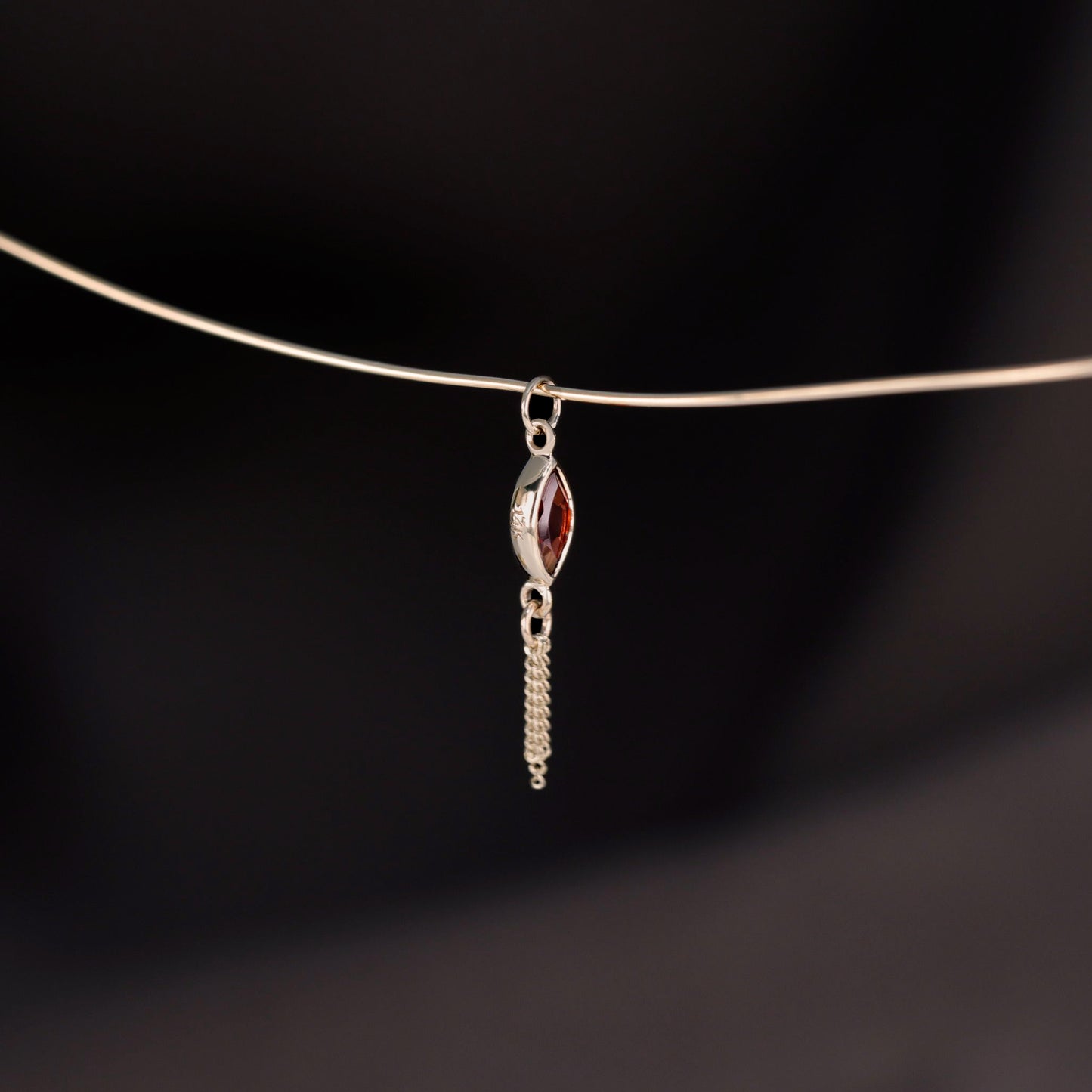 14K gold charm of a marquise-cut Garnet paired with three delicate gold curb chain tassels