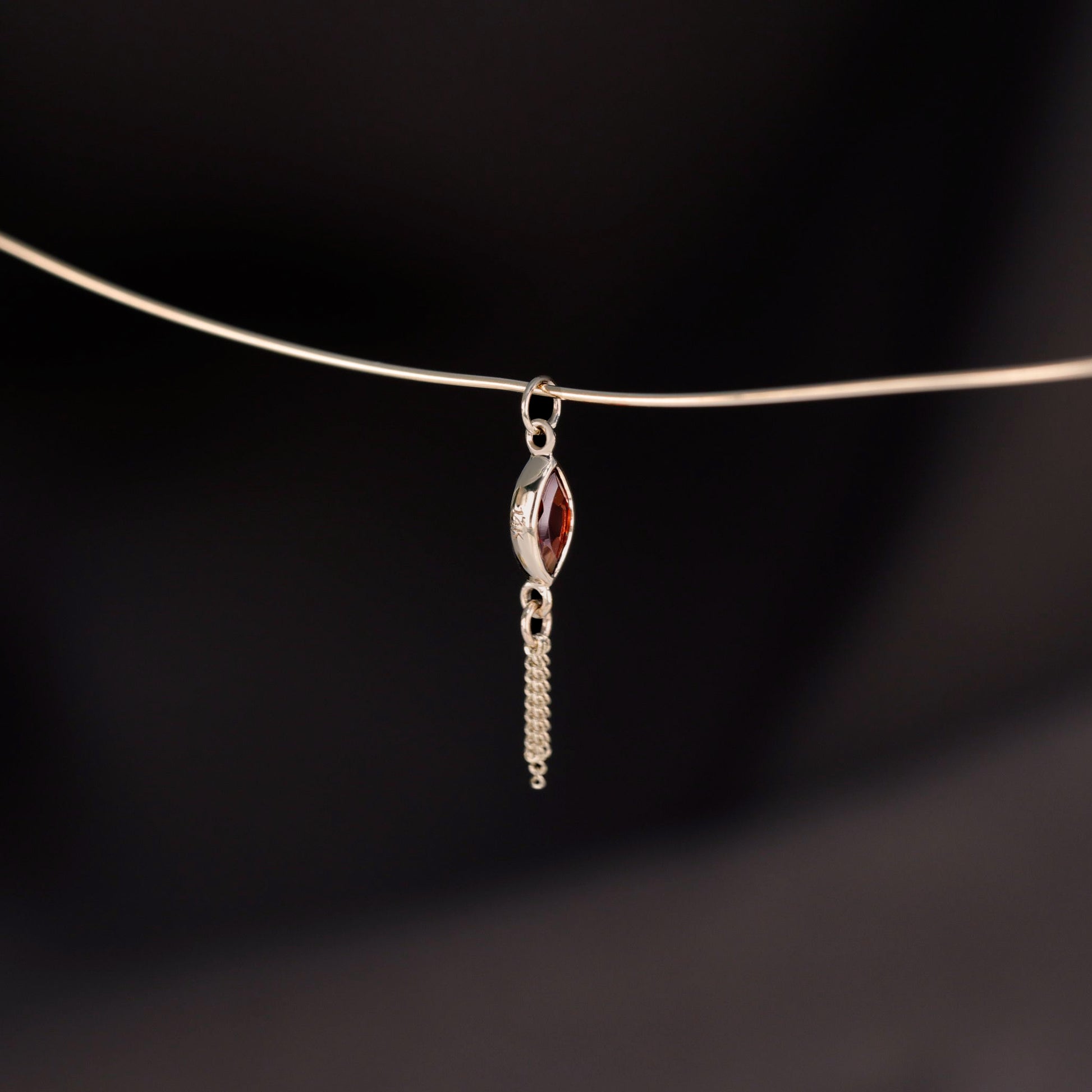 14K gold charm of a marquise-cut Garnet paired with three delicate gold curb chain tassels