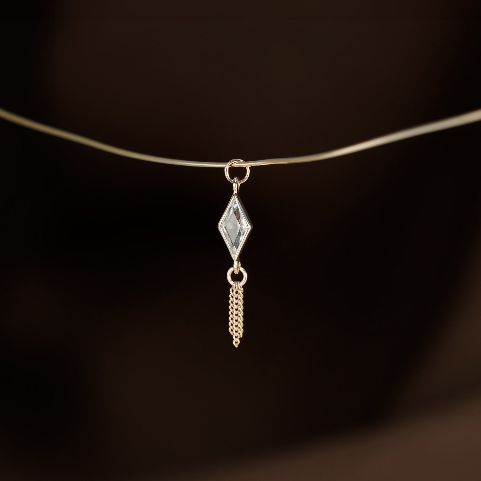 14K gold charm of a kite a Rhombus-cut White Topaz paired with three delicate gold curb chain tassels