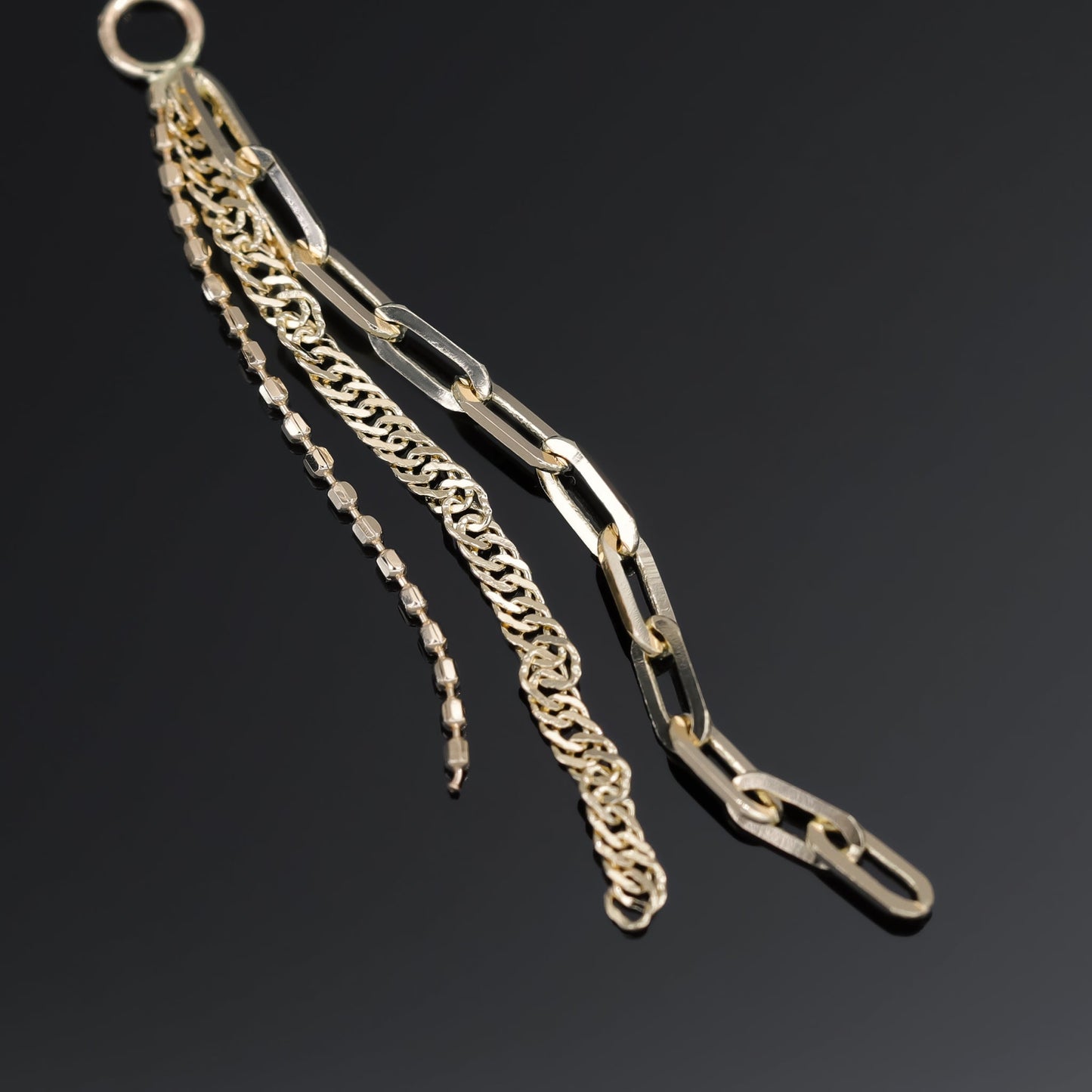 14K yellow gold mixed chain charm that comes with clip chain, box chain and Singapore chain displayed on black surface