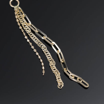 14K yellow gold mixed chain charm that comes with clip chain, box chain and Singapore chain displayed on black surface