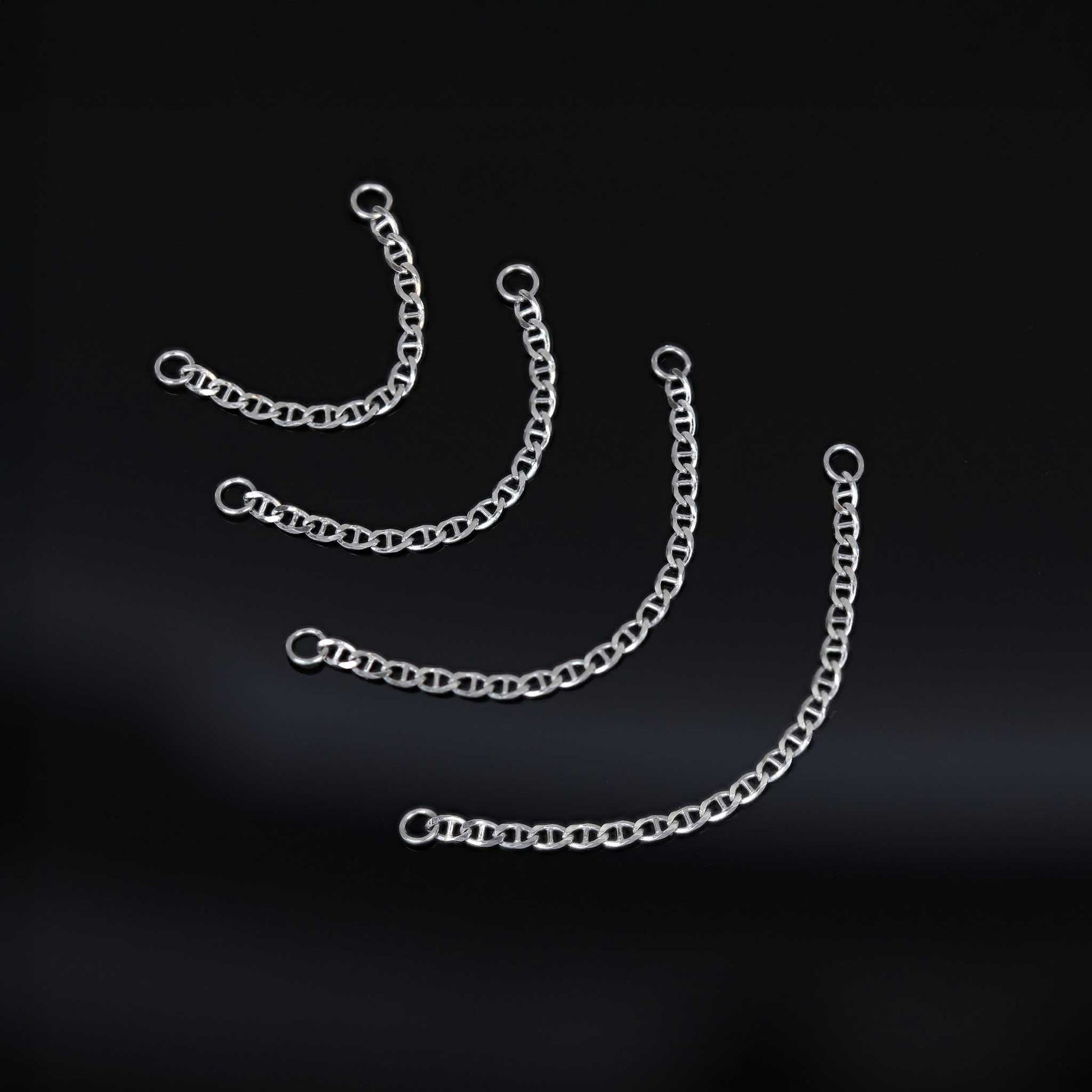 Four types of white gold chain attachments of different lengths on a black background