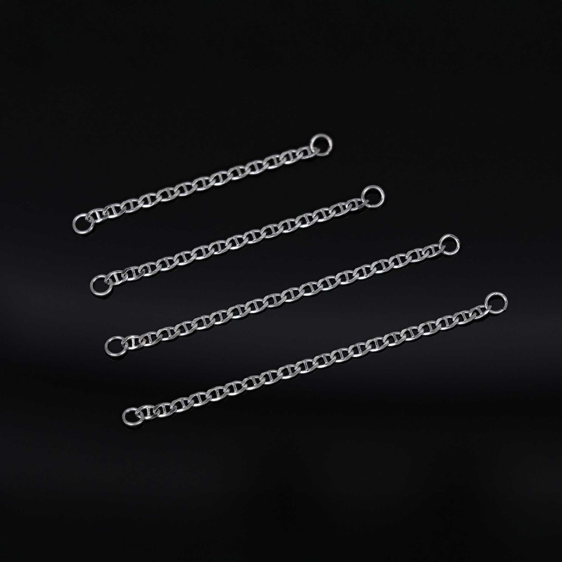 Four white gold chain attachments of varying lengths on a black background