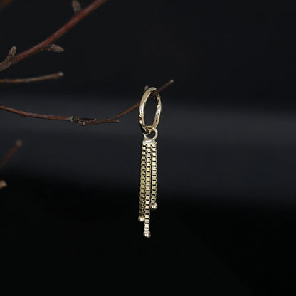Gold chain charm hanging on a branch with black background