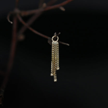 Gold chain charm hanging on a branch with black background
