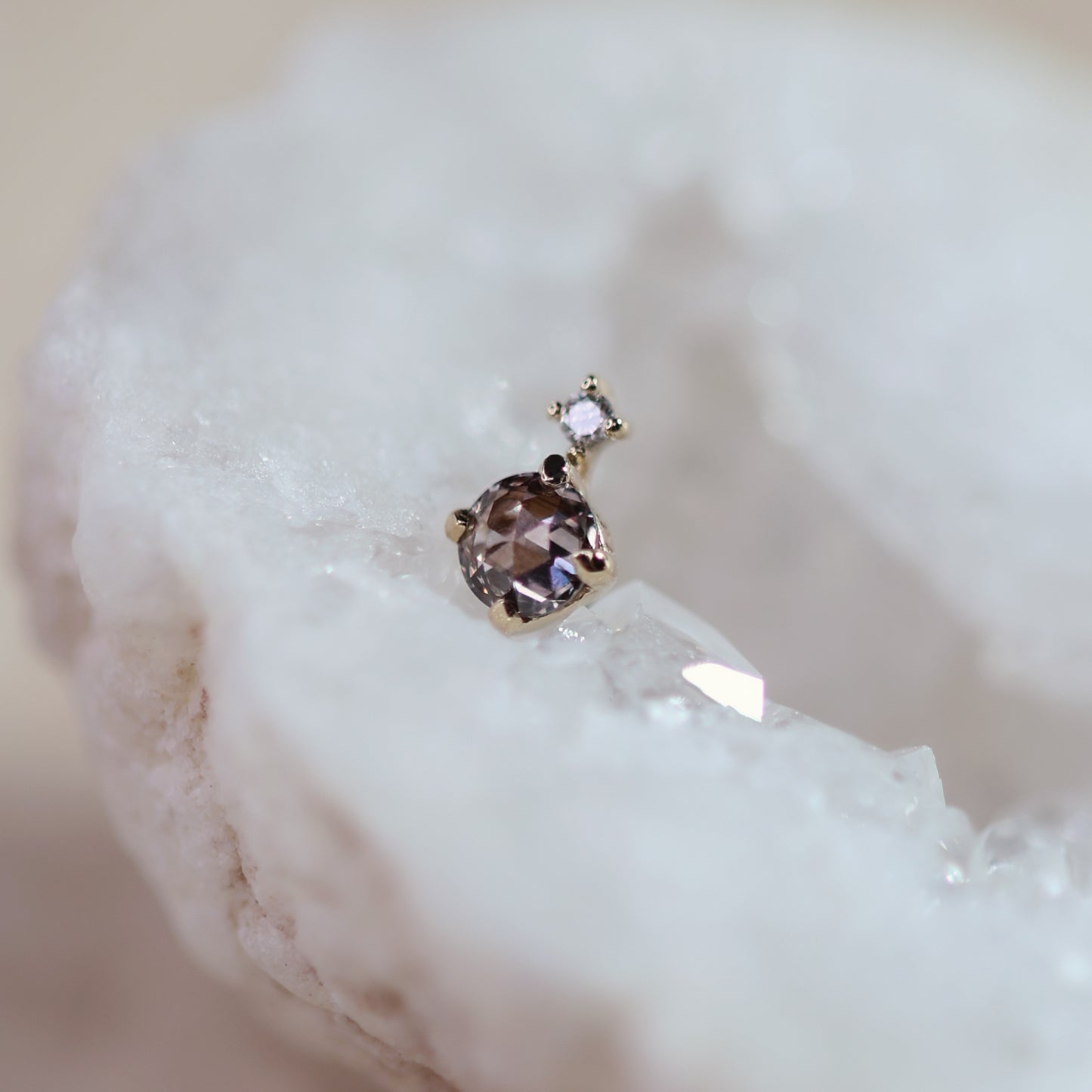 Tiny threadless end studs with brown diamond displayed on a white crystal